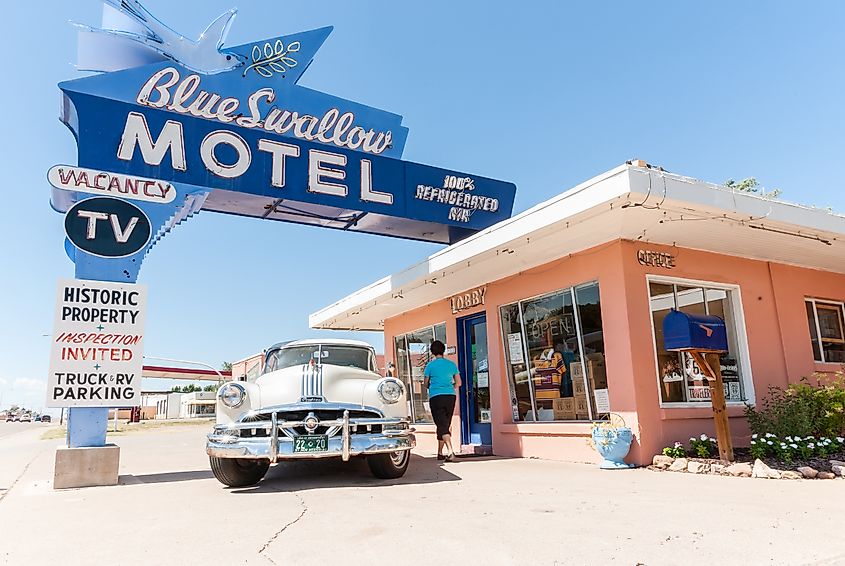 A tourist in a blue top walks up to the lobby door of the Blue Swallow Motel in Tucumcari, New Mexico