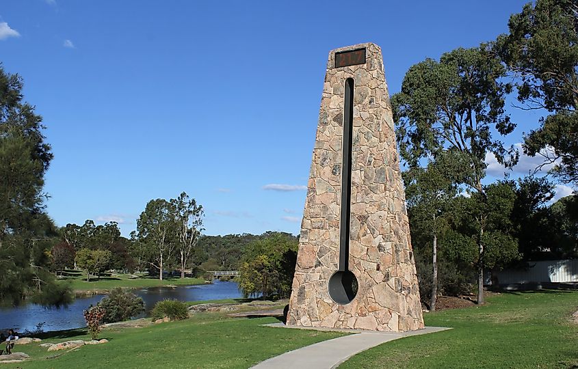 The Big Thermometer at Quart Pot Creek in Stanthorpe, Queensland, Australia, surrounded by grass, a pathway, trees, and water.