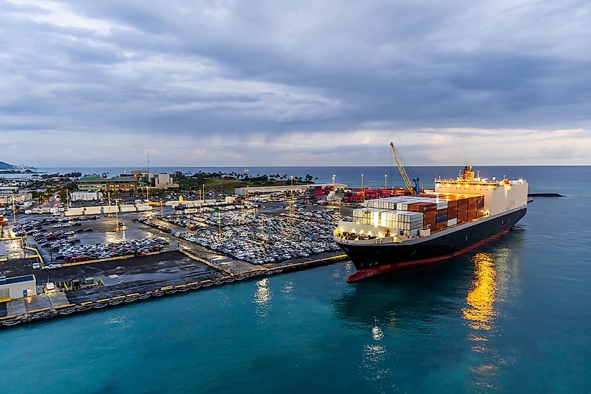 A harbor in Honolulu, Hawaii, with a docked container ship unloading cargo.