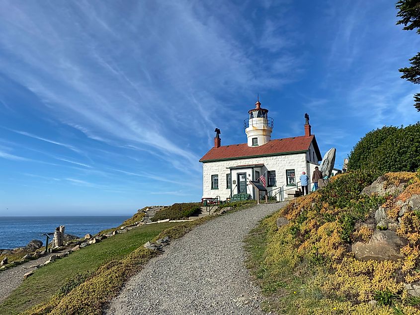 A old fashioned lighthouse tops an oceanside hill.