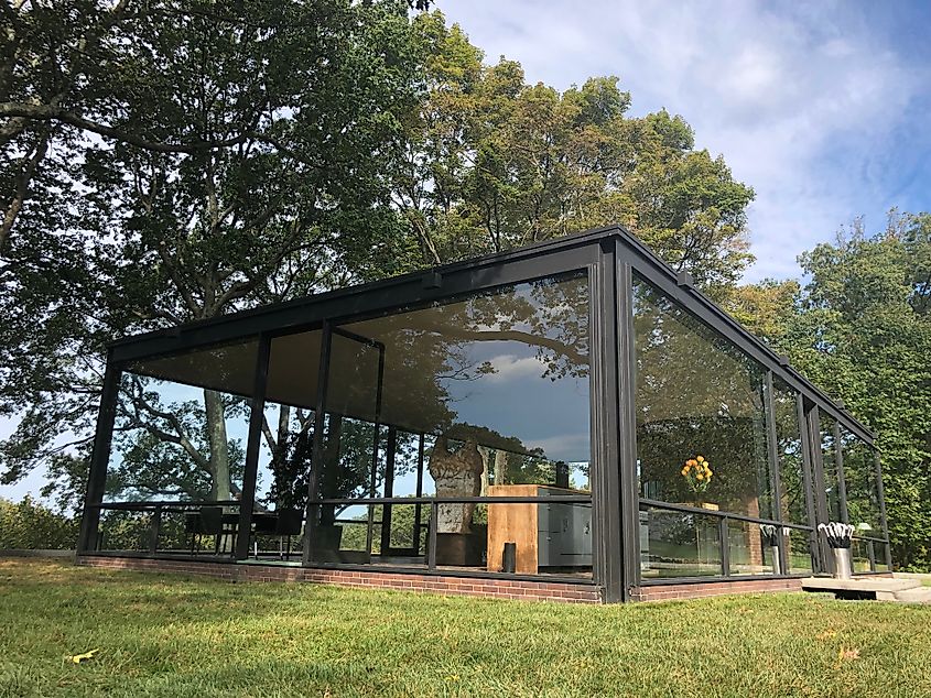 The Glass House by Philip Johnson in New Canaan, Connecticut, featuring its sleek modernist design with transparent walls surrounded by a lush landscape.