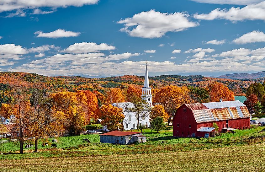 Congregational Church and farm with red barn at sunny autumn day in Peacham, Vermont.