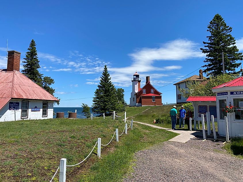 Two men chat on the grounds of a lakeside light station and complimentary structures.