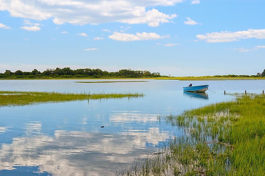 Tranquil view Niantic Connecticut salt marsh in summer with blue sky and blue boat reflections of cumulus clouds in still water with copy space, saltwater tidal marsh, East Lyme
