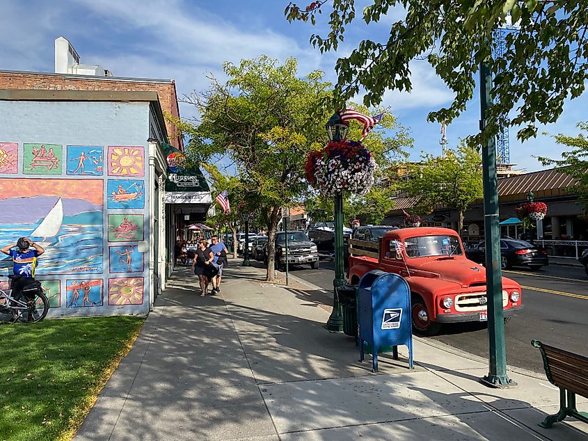 A man on a bike in front of a colorful mural, and a red antique truck frame a small town commercial strip.