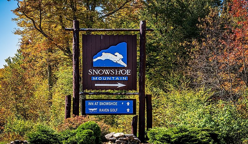 Information sign for mountain ski resort town, small city in West Virginia with direction for inn at Snowshoe and raven golf course in colorful autumn season