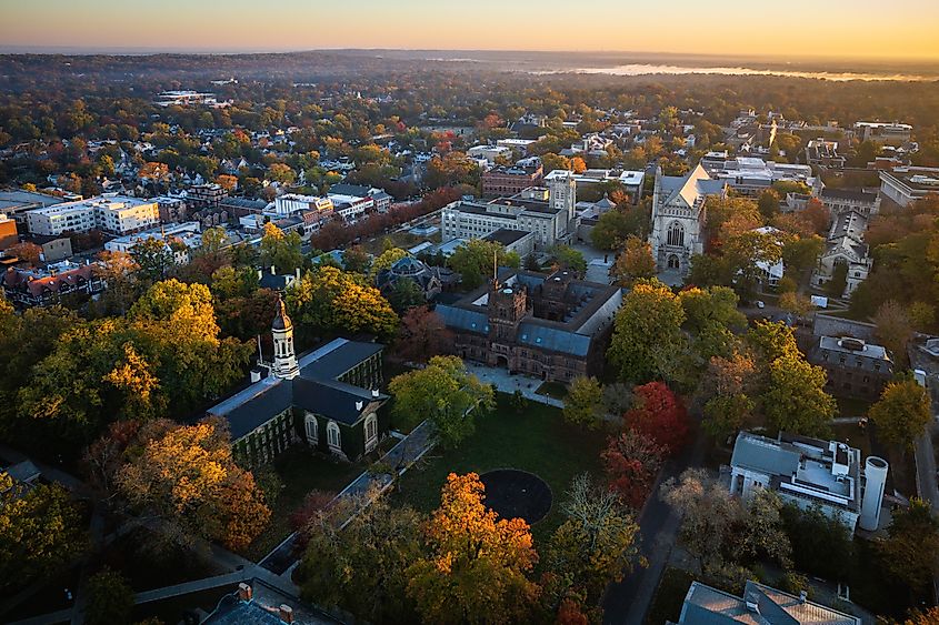 Drone view of a sunrise over Princeton, New Jersey, casting warm light over the town's historic architecture and lush greenery.