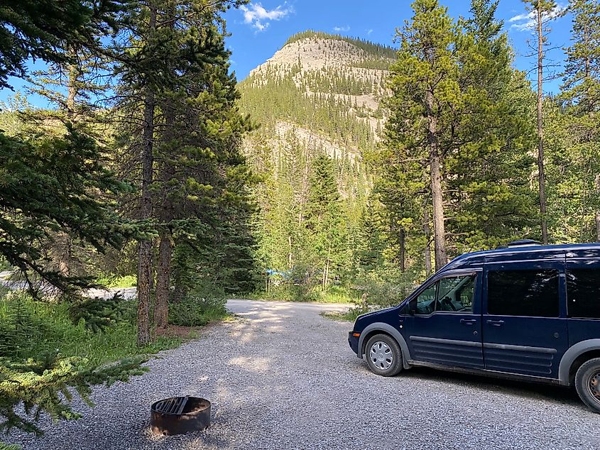 A blue Ford Transit Connect camper van parked at a lovely campground in the Canadian Rockies. 