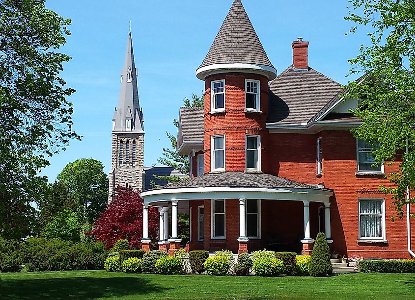 A Victorian house with a turret and large curving veranda, with a church in the background, near Goderich, Ontario, Canada.