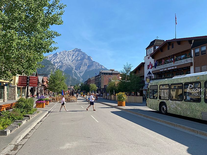 A couple crosses the Main Street in Banff in order to catch the bus. A massive mountain stands in the background