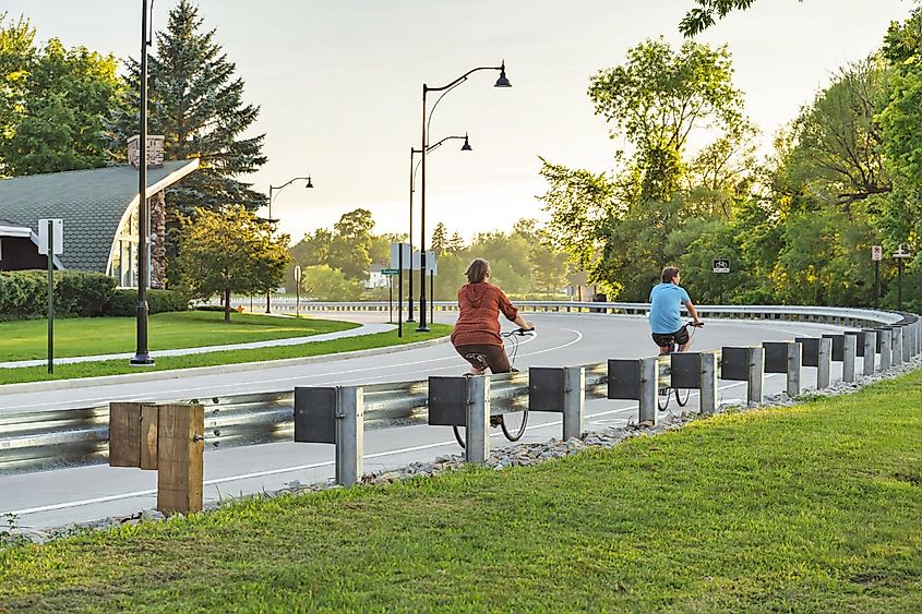 Marinette, Wisconsin: Men and women ride bikes together on the sunset on the lake side to exercise in the evening