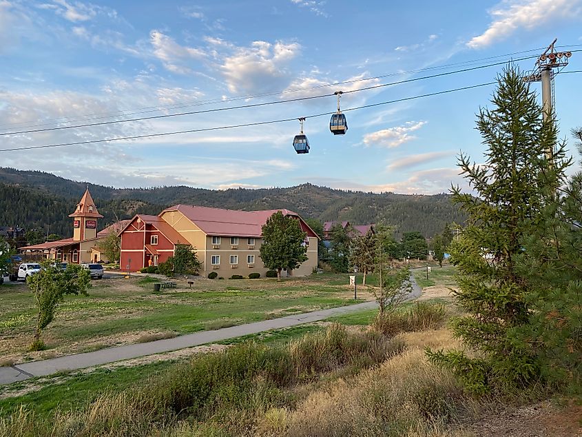 Two gondolas pass over a ski resort in the summer off-season.