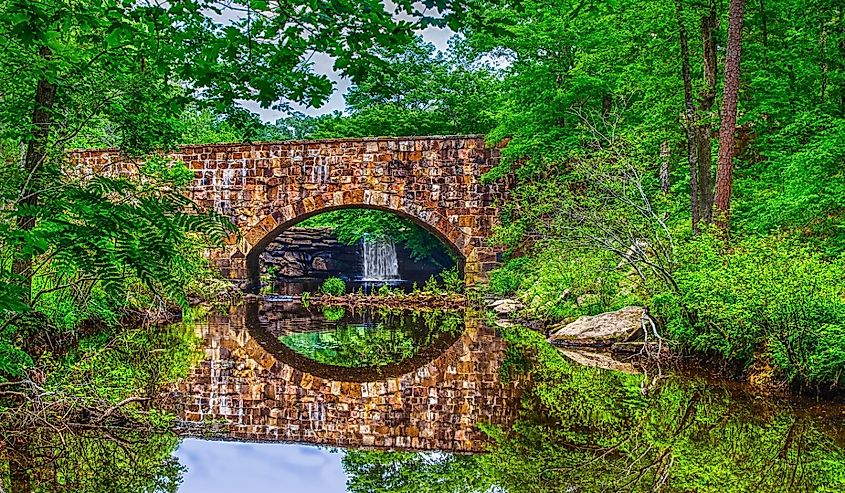 Bridge, waterfall and foliage reflections of scenic Davies Bridge in Petit Jean State Park near Russellville, Arkansas.