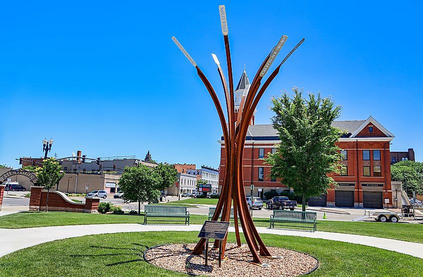 The "Our Ties That Bind" sculpture at Wooster Green in Bowling Green, Ohio, featuring eight pillars with laser-cut words on stainless steel plates that light up at night.