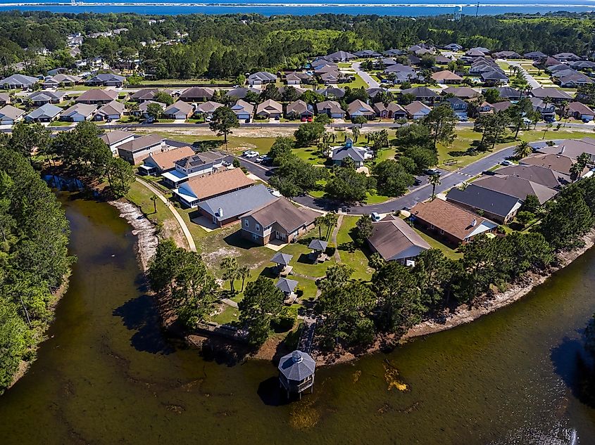 Aerial view of residential neighborhood with lagoon in Navarre Florida. Scenic residential landscape with houses amidst lush green trees foliage on a sunny day.