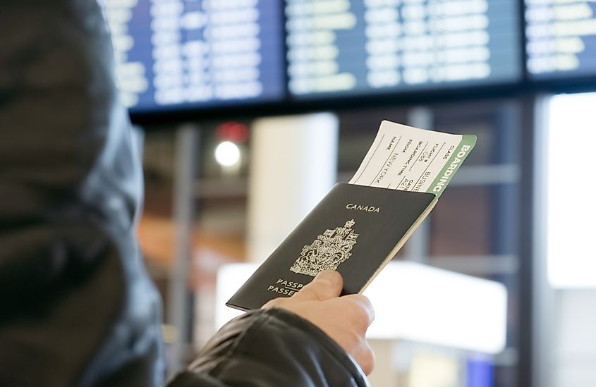 A man with a Canadian passport and boarding pass looks at the airport departure