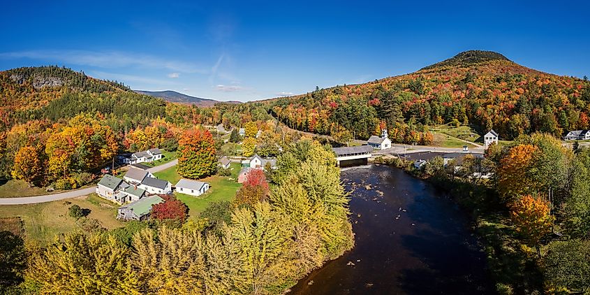 A covered bridge in Stark, New Hampshire, surrounded by vibrant fall foliage, reflecting the classic charm of New England in autumn.