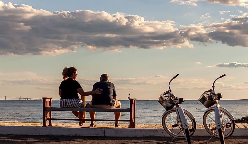 Two people sitting by the waterfront in Rock Hall, Maryland with two bikes.