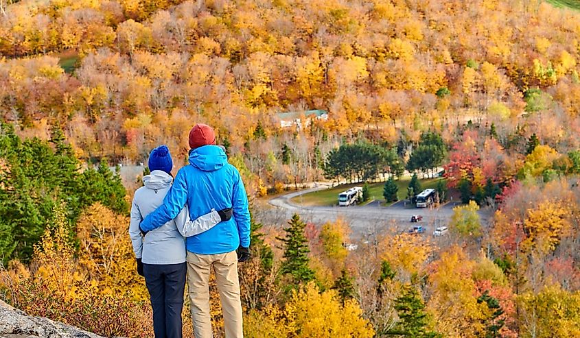 Couple hiking at Artist's Bluff in autumn. Fall colours in Franconia Notch State Park.