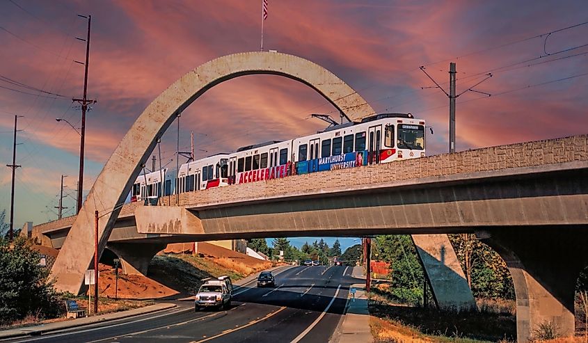 Light rail train travels under a concrete arch on route from Hillsboro to Portland, Oregon