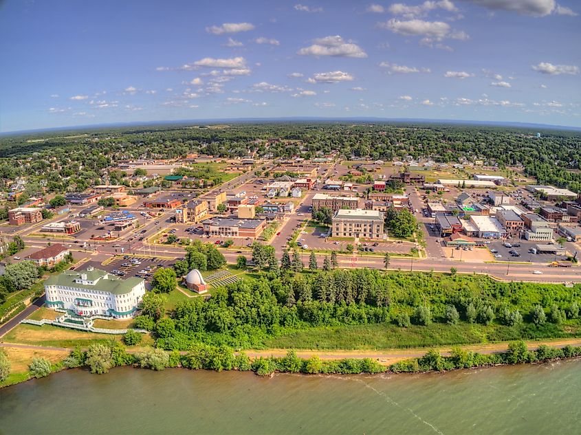 Aerial view of Ashland, Wisconsin, a small town on the shore of Lake Superior, with its waterfront, buildings, and surrounding natural landscape.