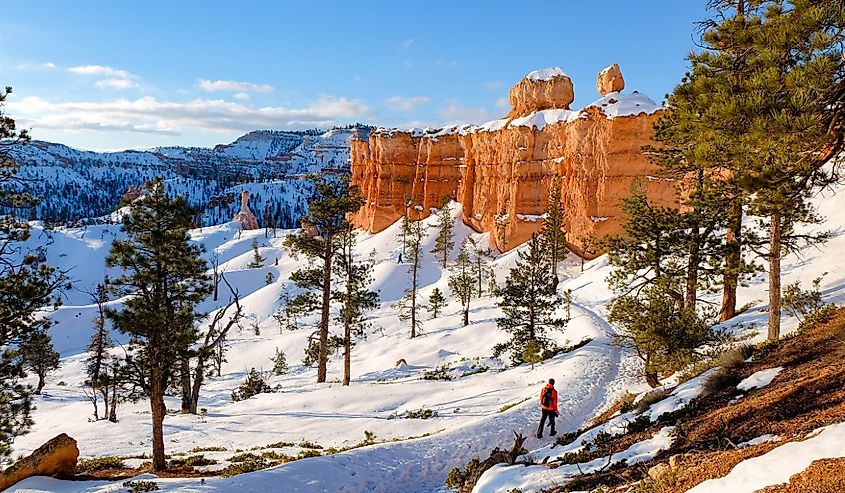 A hiker ventures along the snowy trails of Utah's Bryce Canyon National Park in winter.