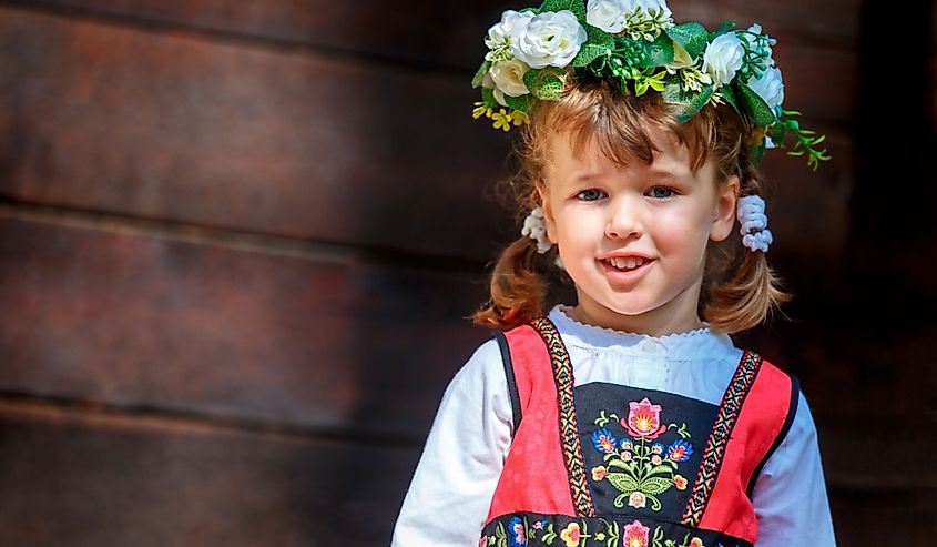 Adorable little girl in Swedish traditional clothes wearing flower wreath during Midsommar festival celebration