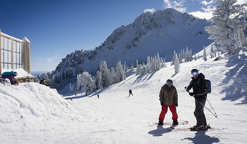 A skier and a snowboarder enjoy the snow and sun at the top of the lift at Snowbasin in Huntsville Utah.