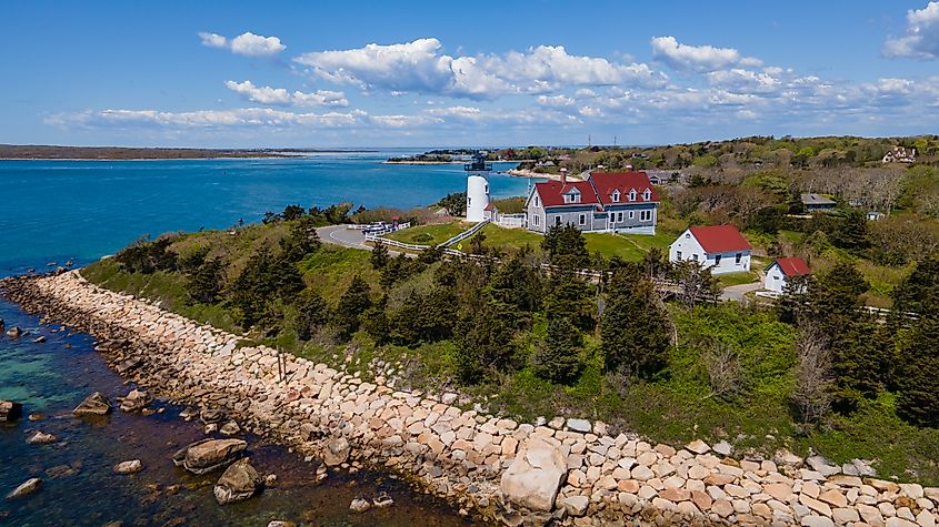 Nobska Lighthouse in Woods Hole, Cape Cod, standing on a grassy hill overlooking the coastline, with its classic white tower and red-roofed keeper's house nearby.