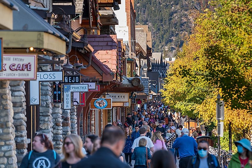 Banff, Alberta, Canada - October 06 2022 : Crowds of people shopping on Banff Avenue in a autumn sunny day.