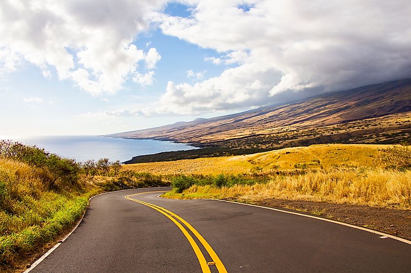 View of the rugged landscape along Piilani Highway in Maui, Hawaiian Islands, with winding roads, coastal cliffs, and lush greenery, forming part of the scenic back route to Hana.