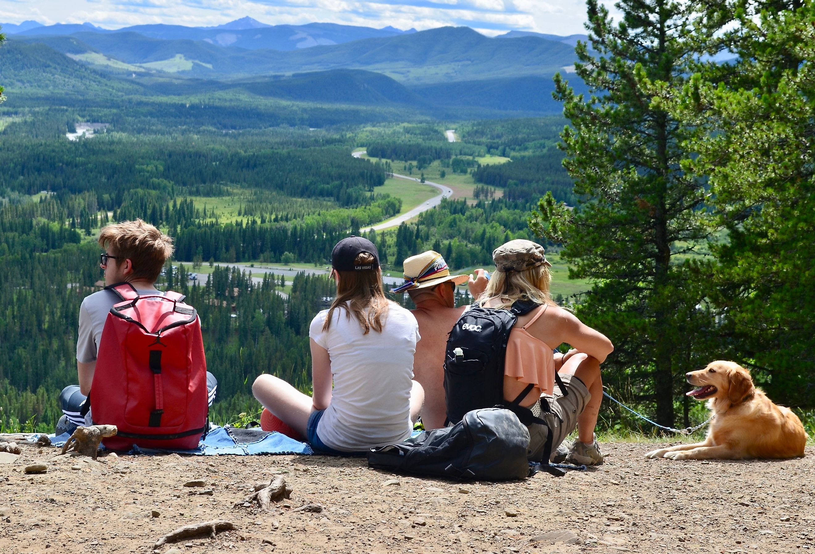 Family with a dog sitting on the ground and enjoying the view from Fullerton Loop Trail in Bragg Creek, Alberta. Image credit AIVRAD via Shutterstock