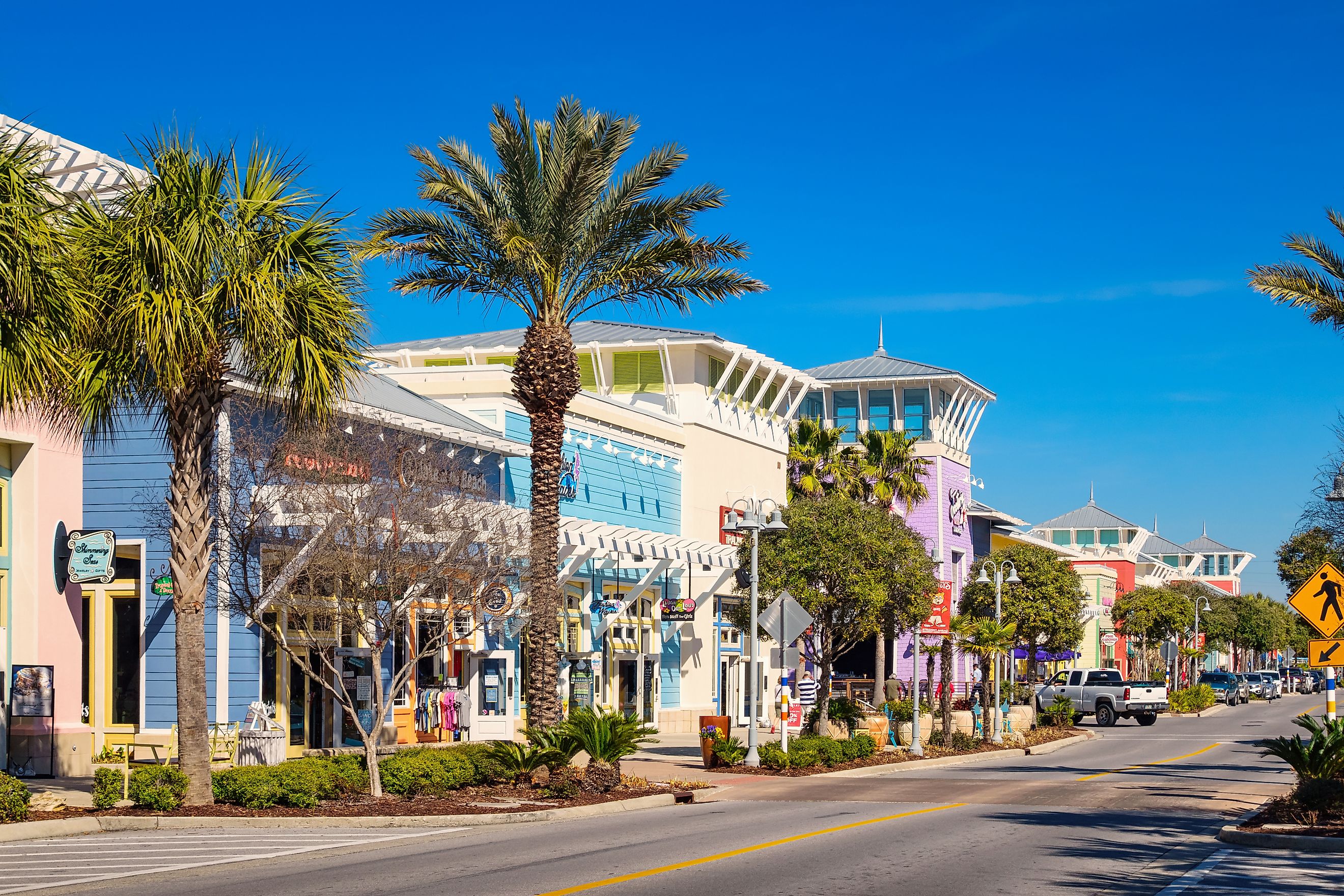 Photo of a street with colorful storefronts in downtown Panama City Beach, Florida, USA on a clear blue sky day.