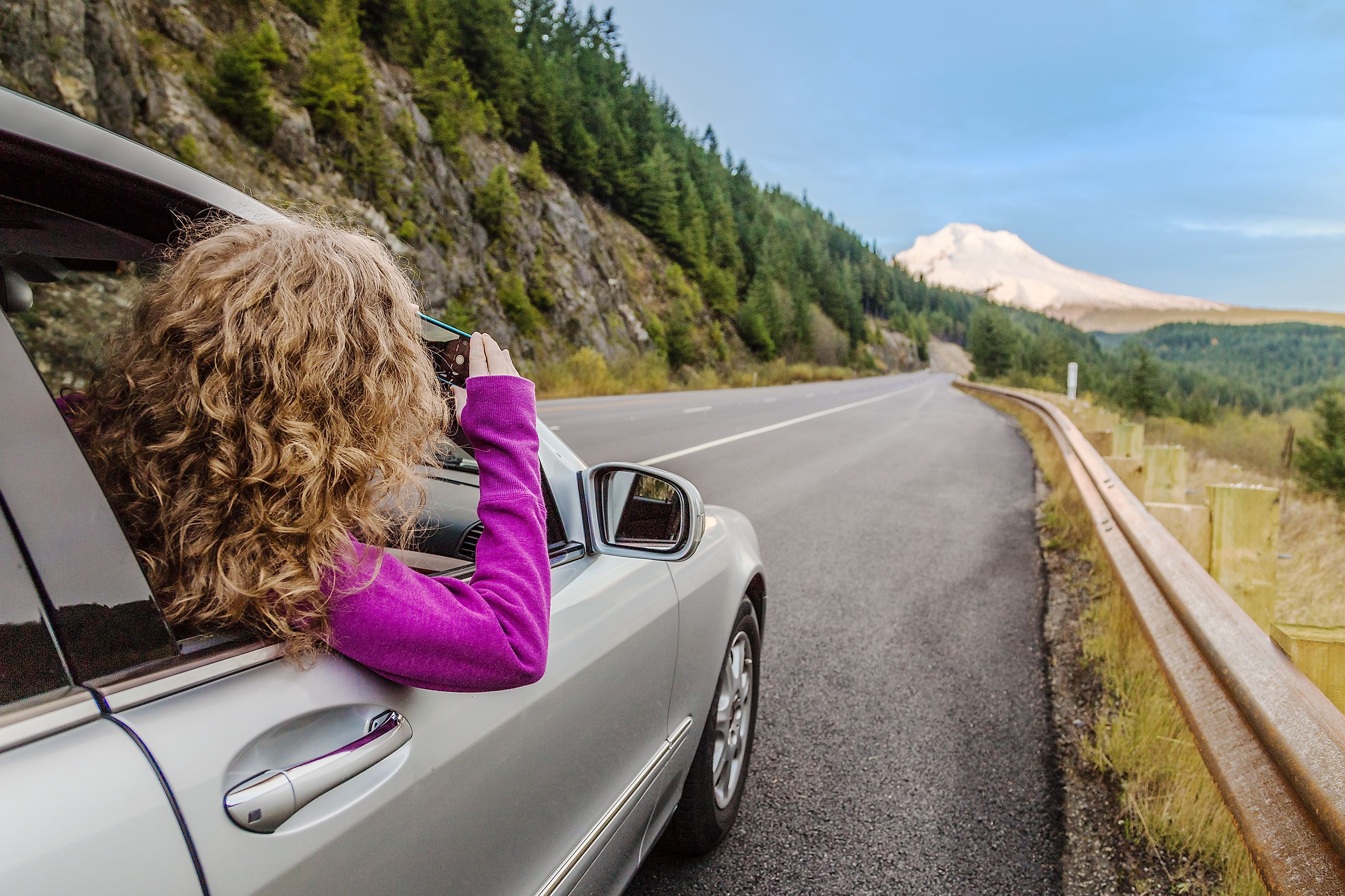 Girl taking pictures of the mount Hood, Oregon from inside of the car