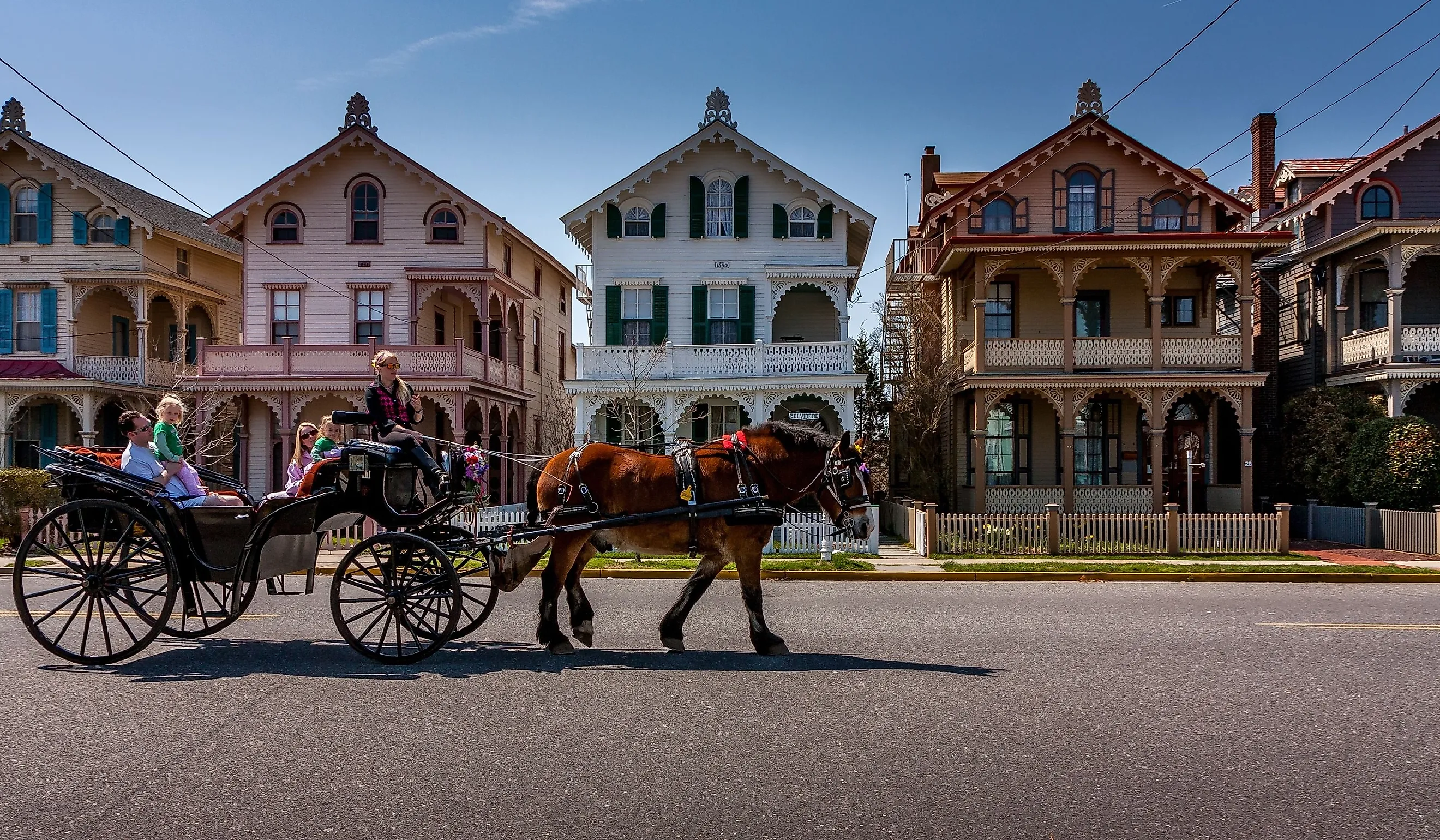 A carriage carries tourists past a row of Victorian "gingerbread" houses typical of Cape May, NJ. Editorial credit: Steve Rosenbach / Shutterstock.com