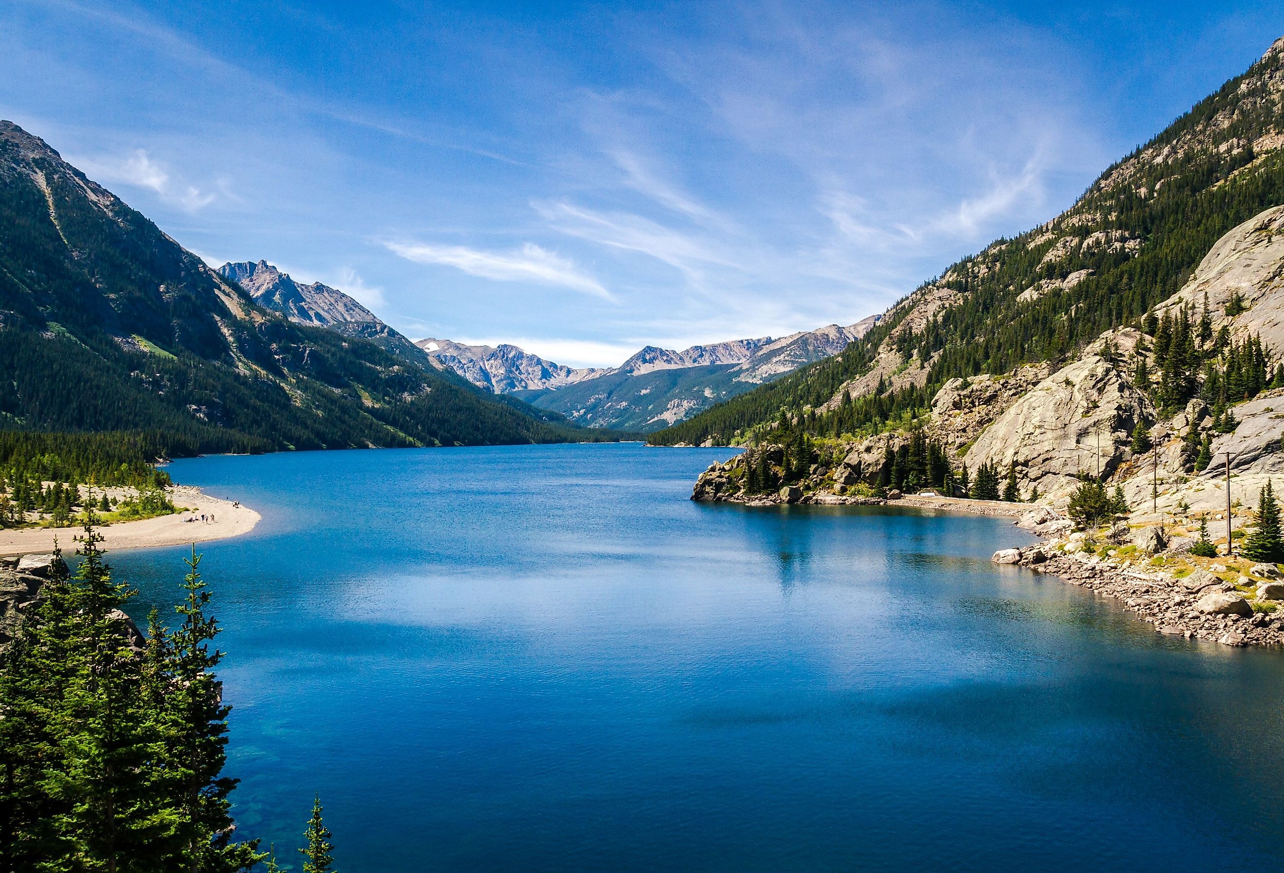 Overlooking the blue waters of Mystic Lake, Montana, surrounded by mountains and with people on the beach.