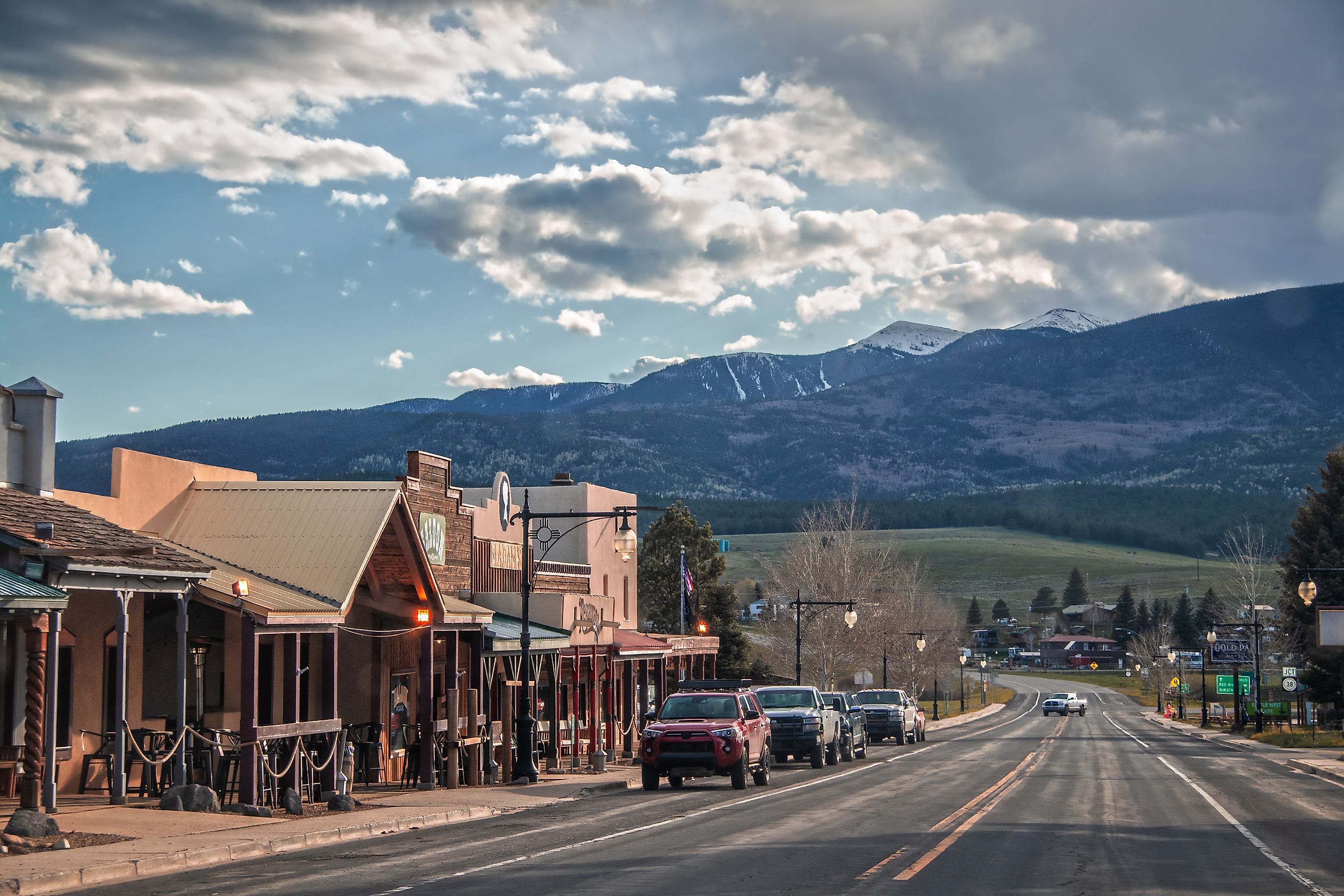 Red River, New Mexico, a small western-style tourist town near the Angel Fire ski resort, with cars parked along the main street and mountains in the background at dusk. Editorial credit: Vineyard Perspective / Shutterstock.com