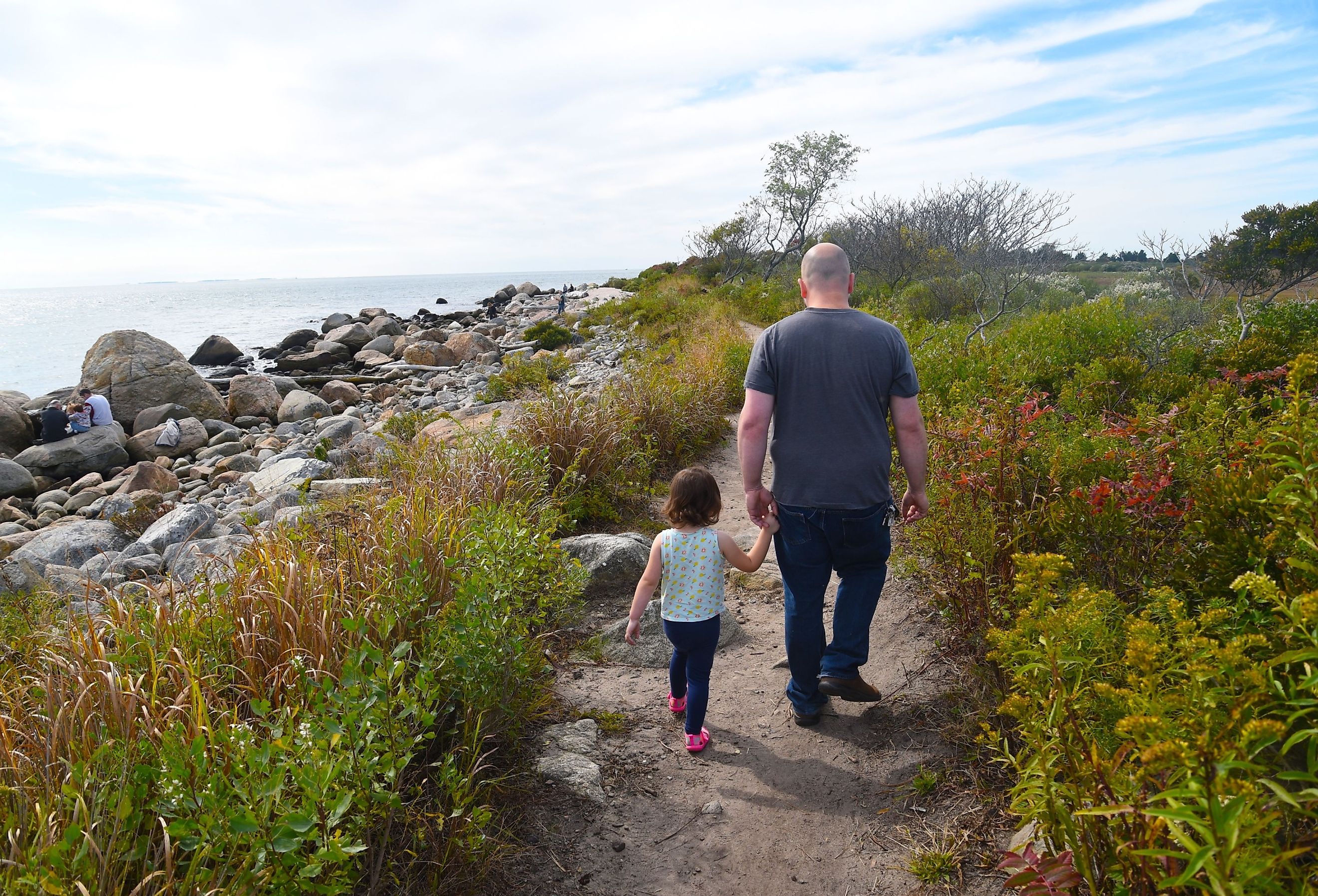 A man walks with his daughter along the coast at Hammonasset Beach State Park in Madison, Connecticut. Image credit Joe Tabacca via Shutterstock.