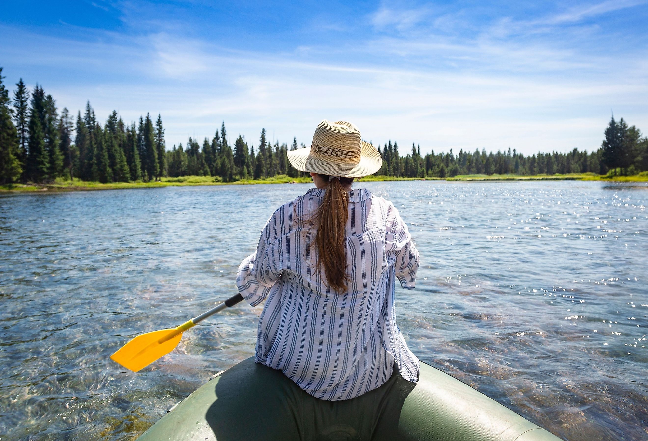 Woman paddling on an inflatable raft while floating the Snake River in Island Park, Idaho.