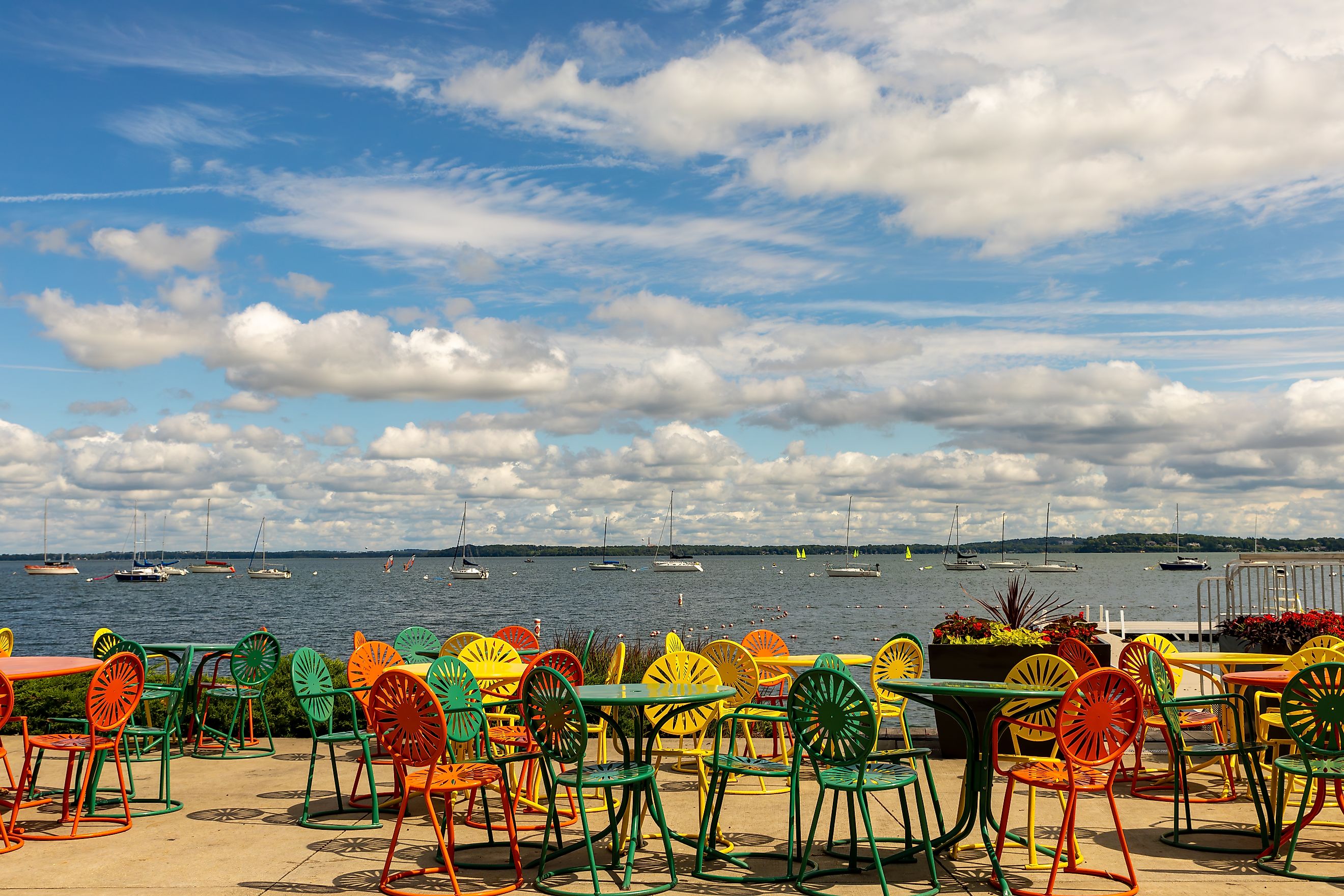 Iconic colorful tables and chairs overlooking sailboats on Lake Mendota at Union Terrace on the University of Wisconsin - Madison campus. Editorial credit: Koeppen Photo / Shutterstock.com