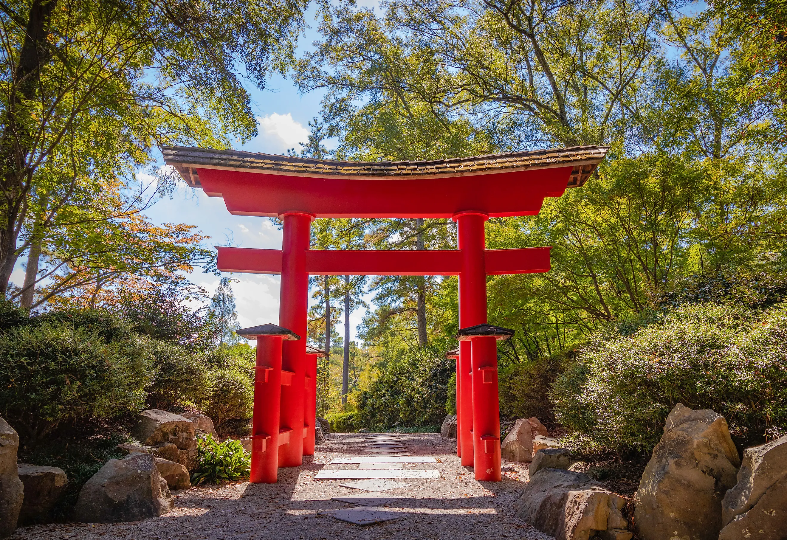 A torii gate stands in the Birmingham Botanical Gardens in Alabama, framed by lush greenery in the soft light of the early afternoon.