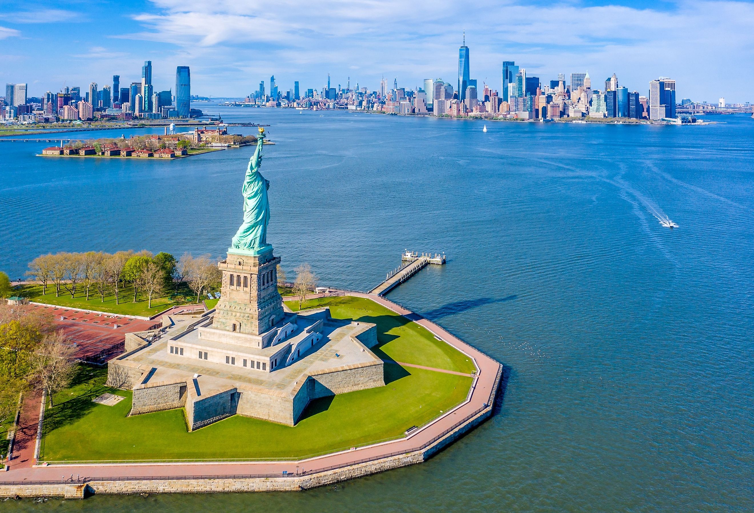 Aerial view of the Statue of Liberty, Ellis Island, and Lower Manhattan Skyline from New York Harbor near Liberty State Park in New Jersey.