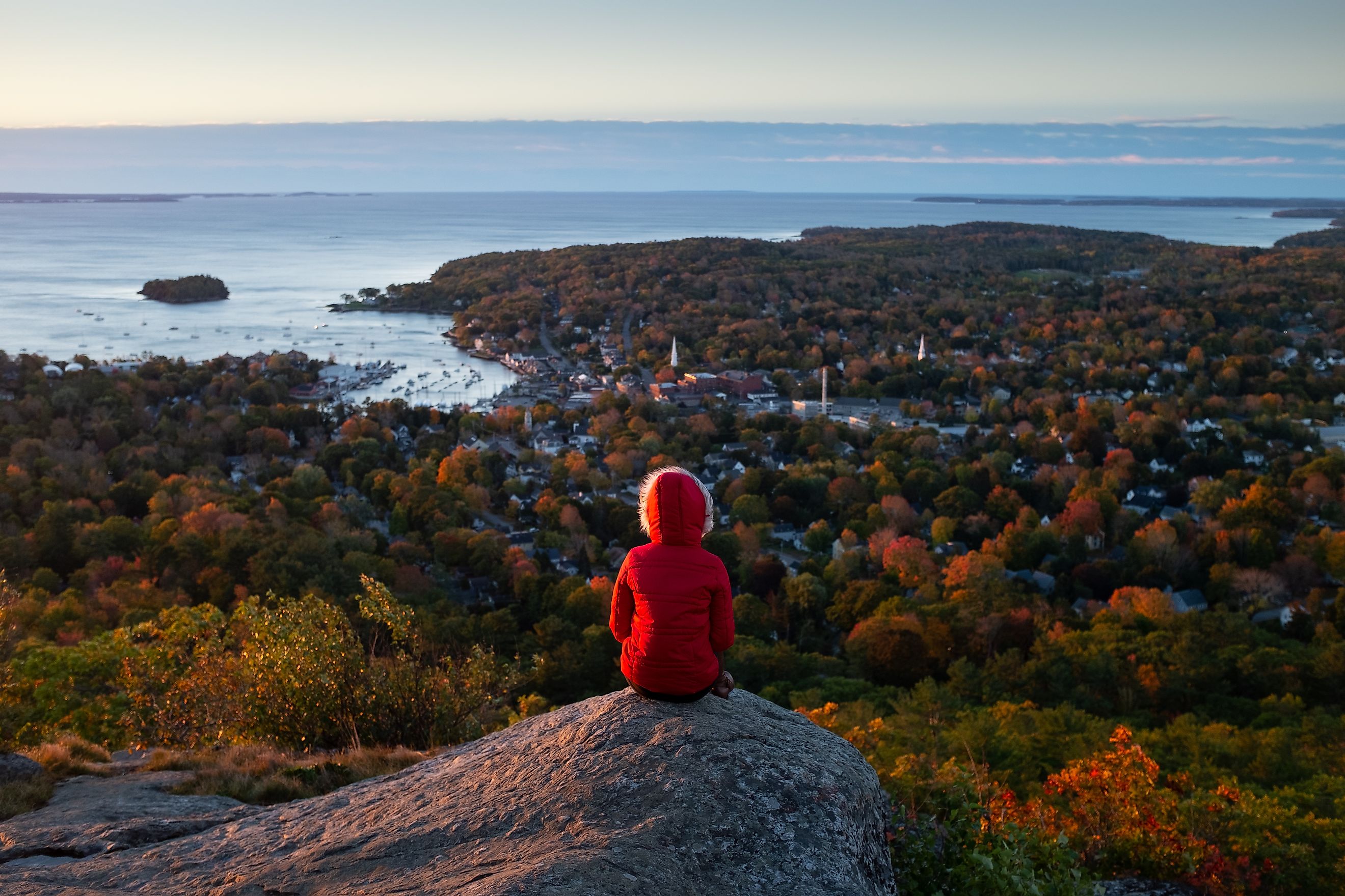 A young woman looks out at the ocean from Camden Hills State Park in Camden, Maine, during the autumn season.