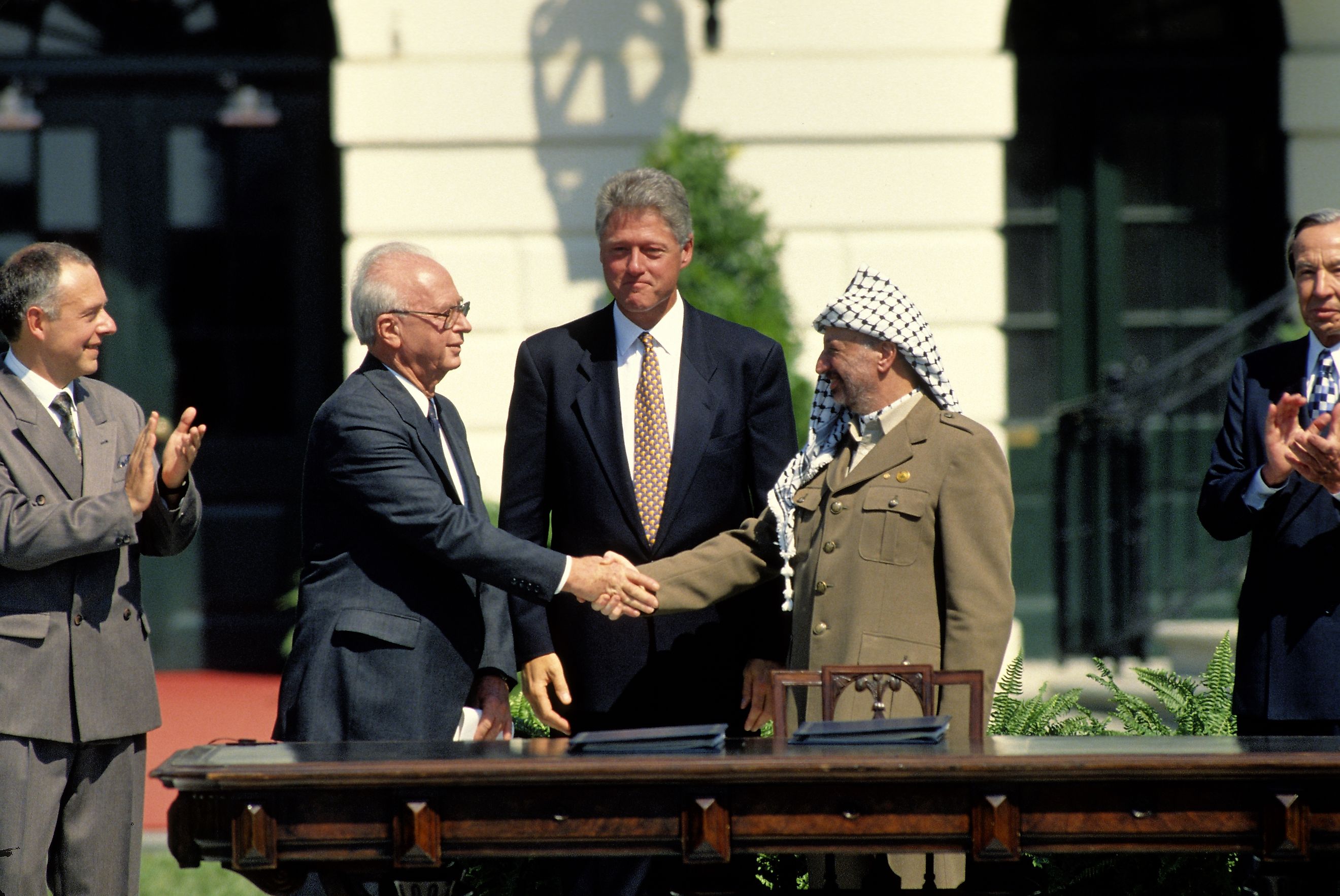 Yitzhak Rabin of Israel and Yasser Arafat of the PLO shake hands on the South Lawn of the White House after signing the Peace Accords, while President Bill Clinton stands behind them. Editorial credit: mark reinstein / Shutterstock.com