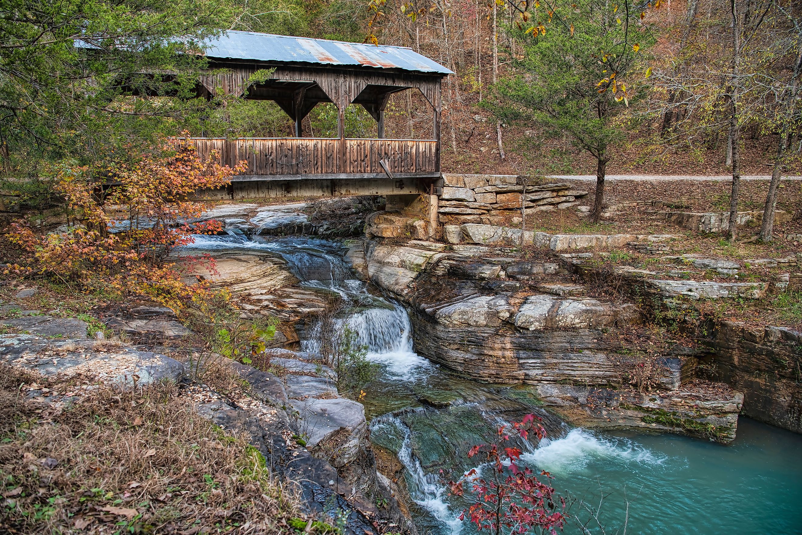 A quaint covered bridge over a cascading waterfall in Ponca, Arkansas.