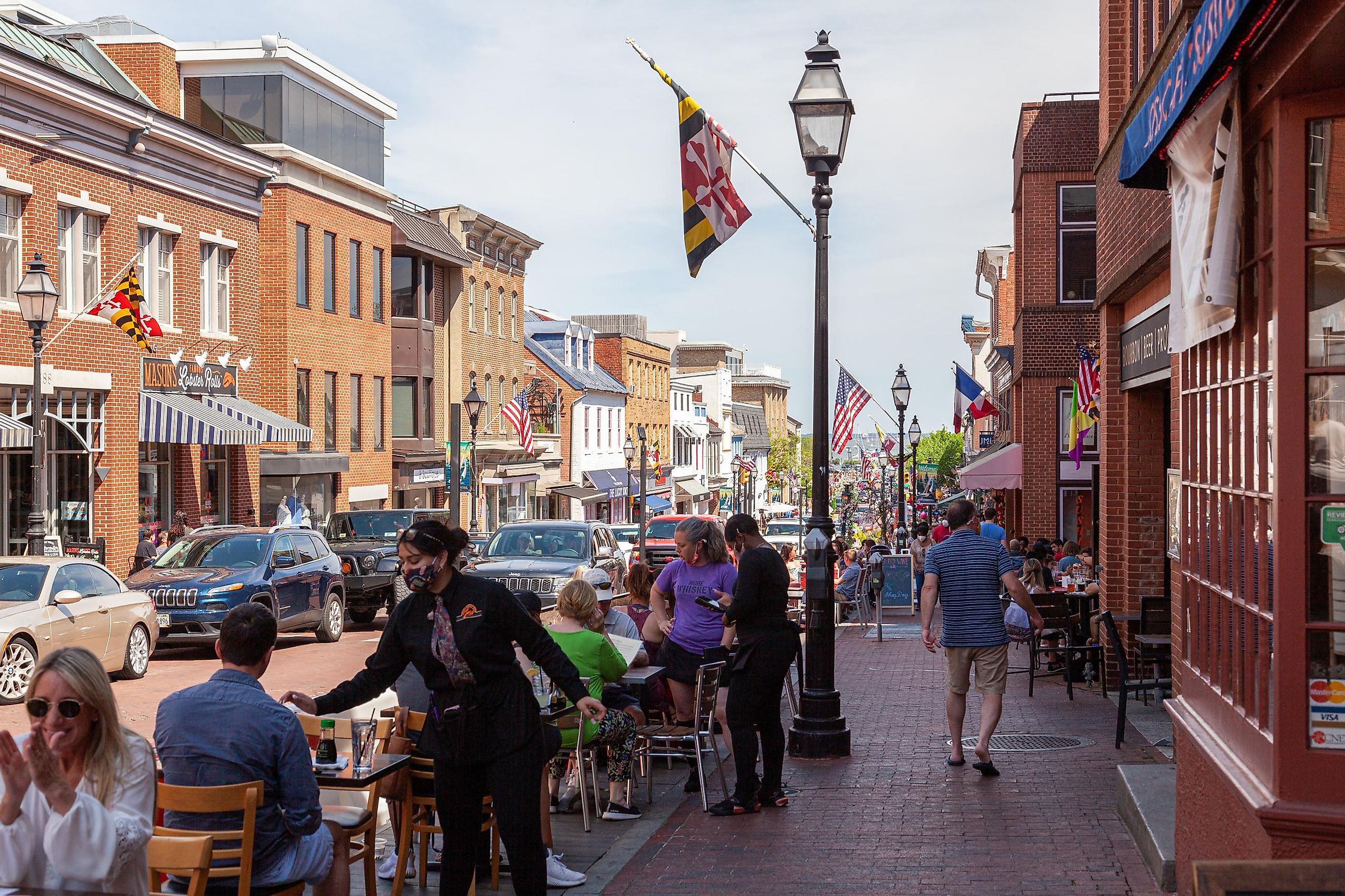 Street view of Annapolis, Maryland with people walking in historic town and people dining outdoor sitting on tables put on street by local restaurants.