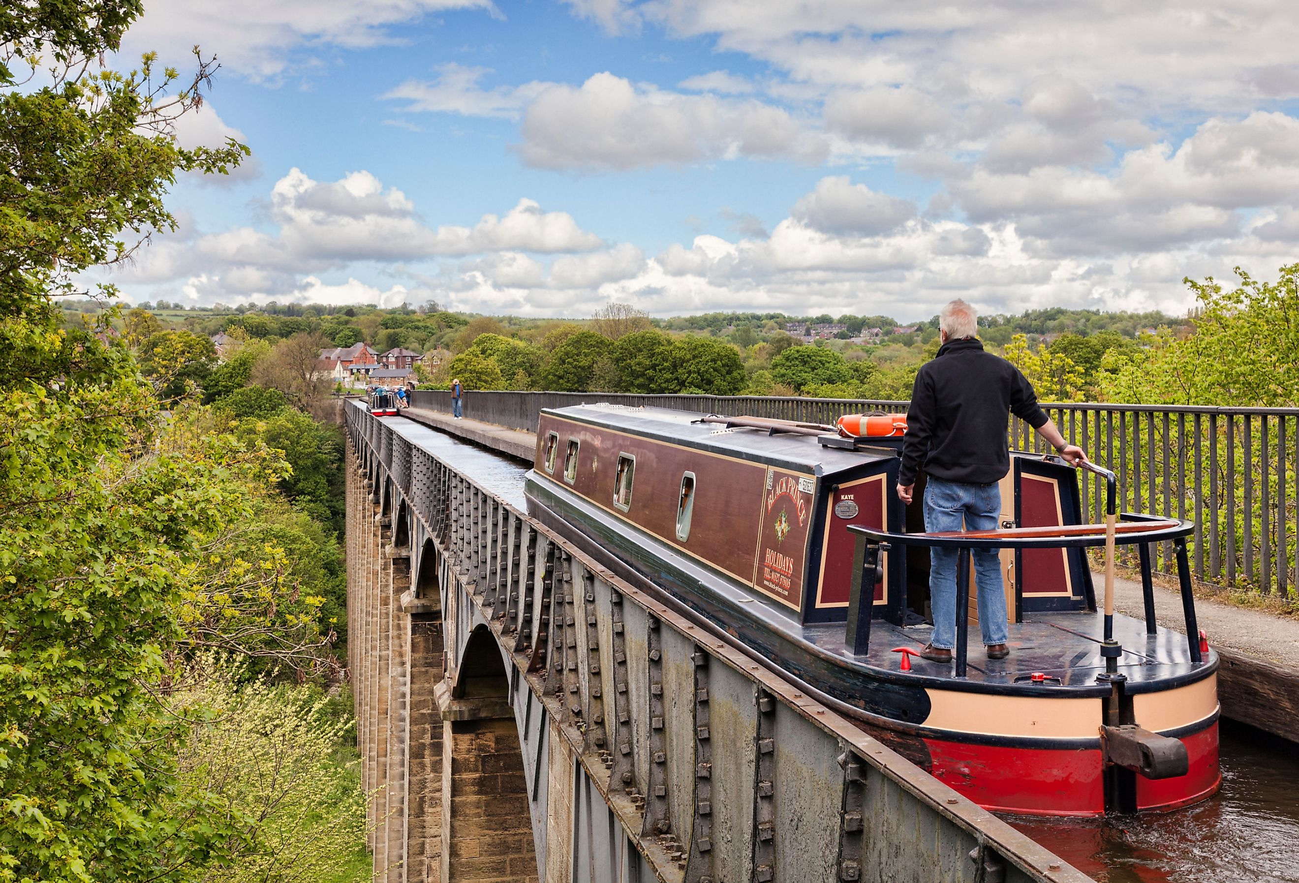 Man steering narrowboat over the Pontcysyllte Aqueduct in Llangollen. Image credit travellight via Shutterstock.