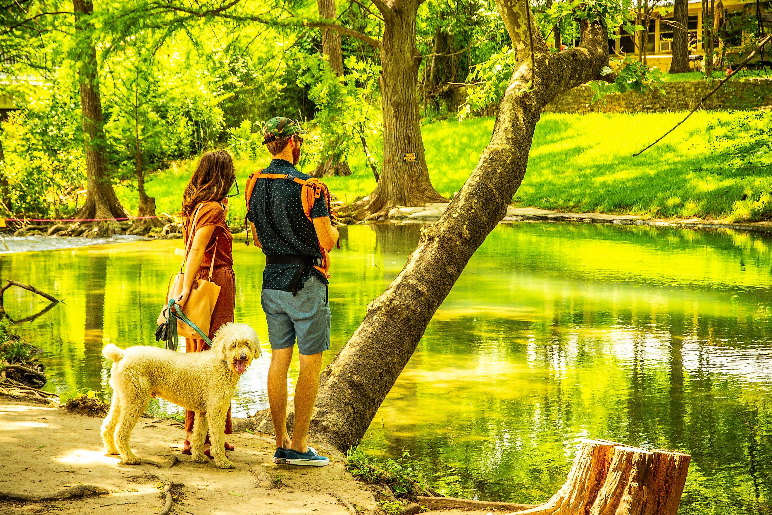 A couple and their dog enjoy the natural beauty of a forested waterway in Wimberley, Texas. Editorial credit: ShengYing Lin / Shutterstock.com