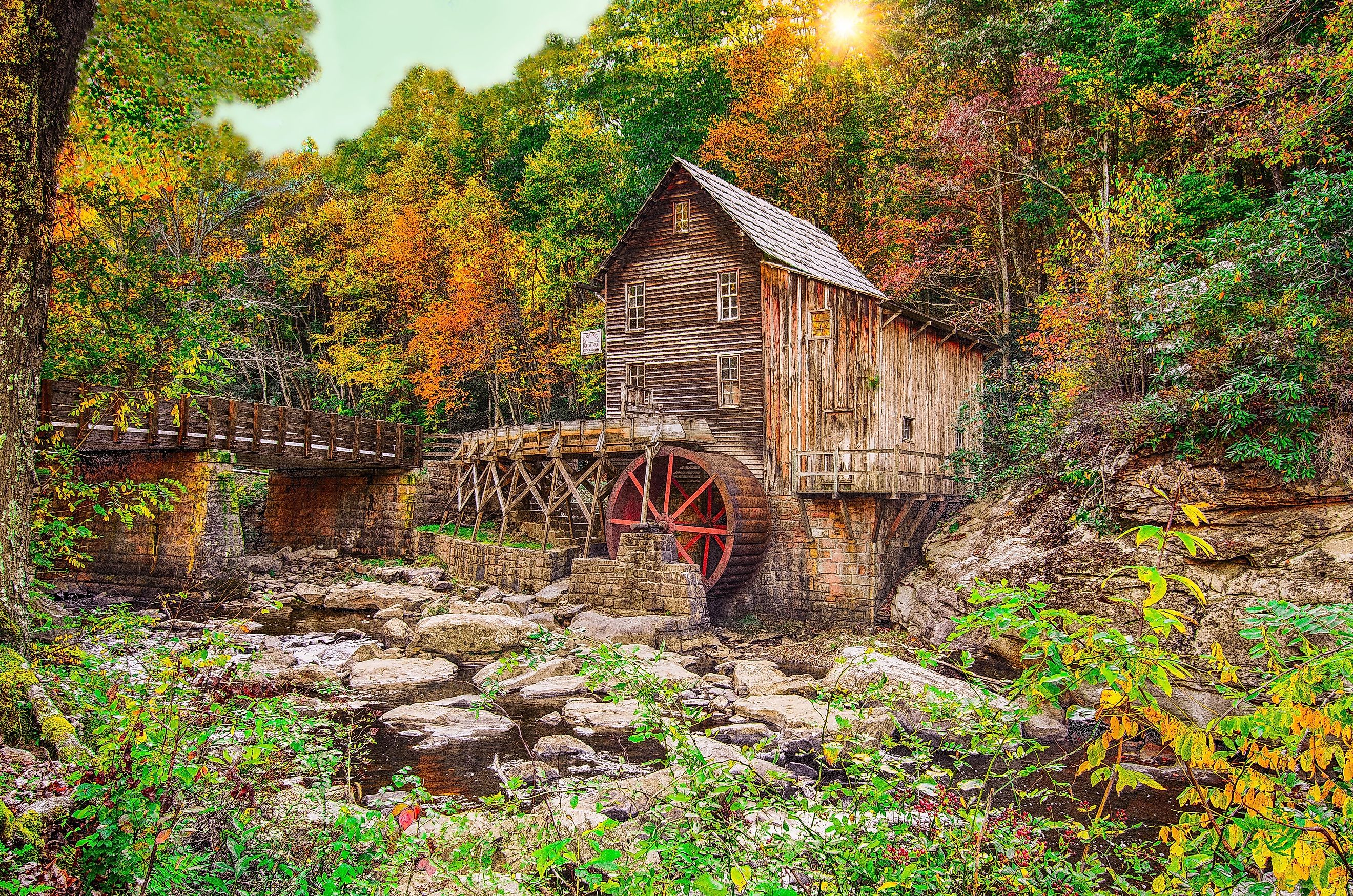 Autumn sun rays illuminating the fall foliage at Glade Creek Grist Mill in Babcock State Park, near Fayetteville, West Virginia.