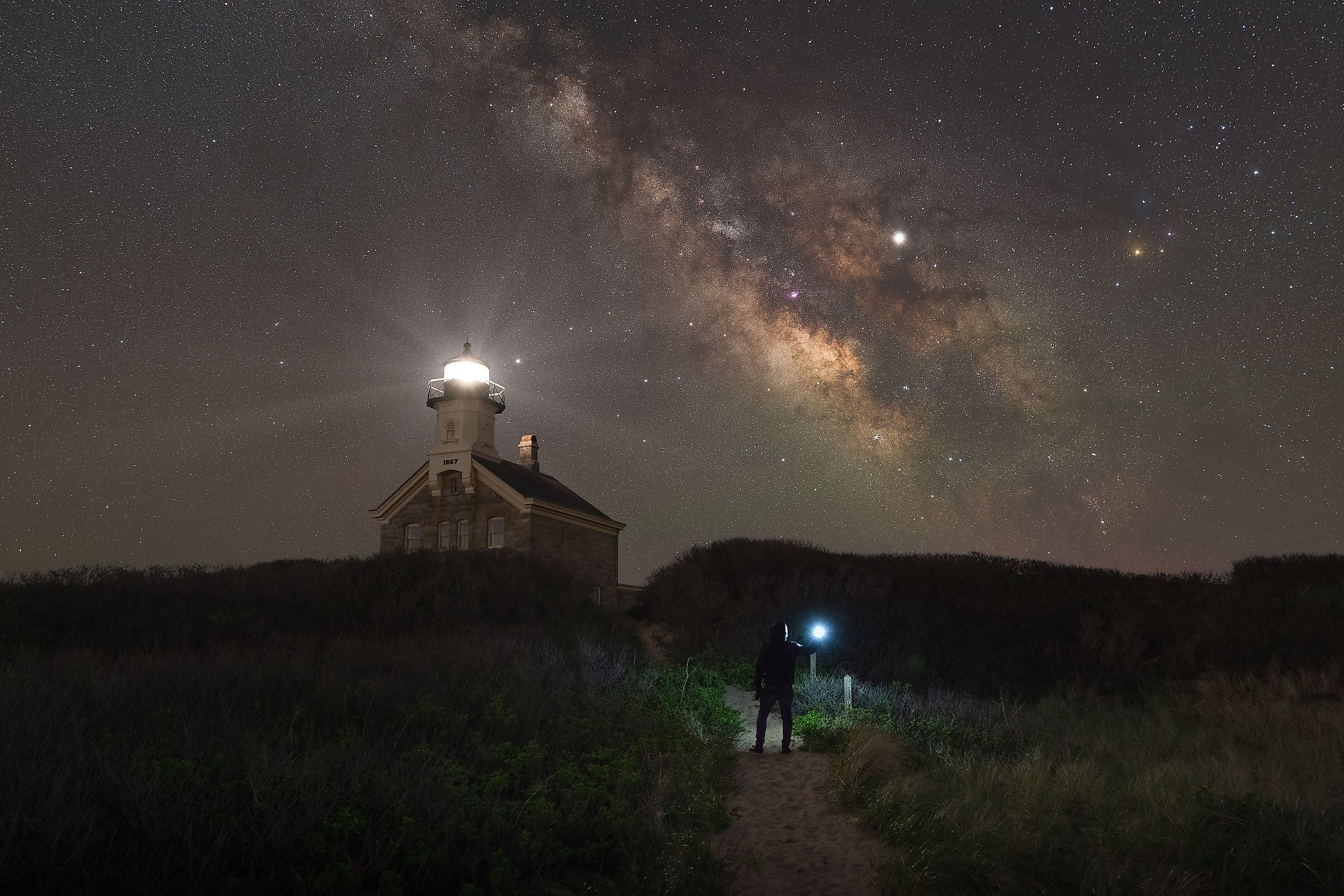 A person stands on a trail leading to Block Island North Light.